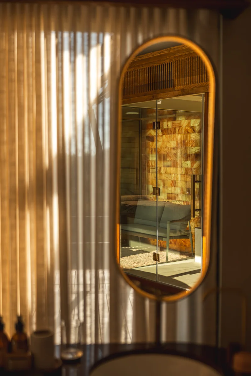 An oval mirror reflecting the suite through linen