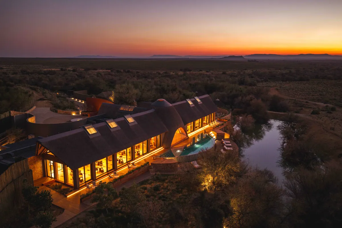 The main lodge at dusk, lit from within beside the water