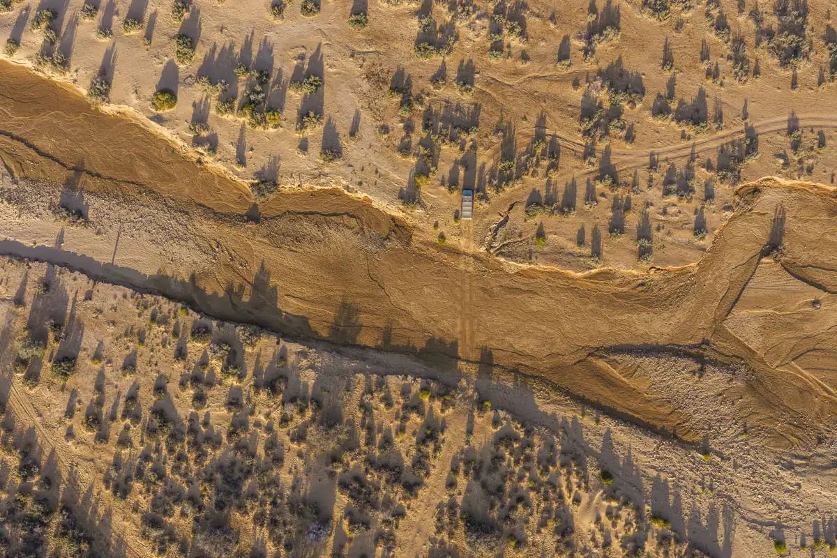 A dry riverbed winding through the scrub from above
